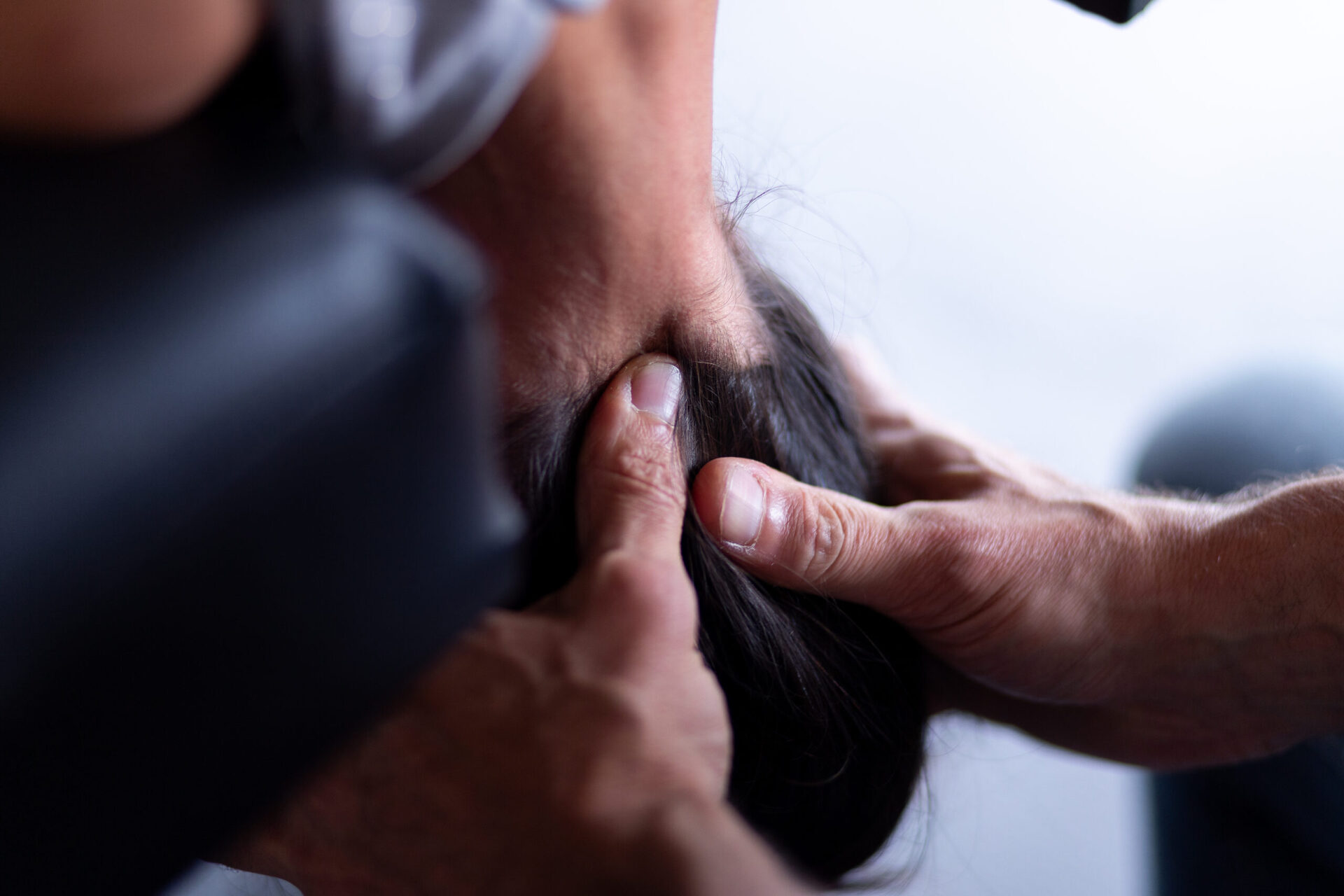 Las manos de un profesional trabajando la zona cervical de una paciente